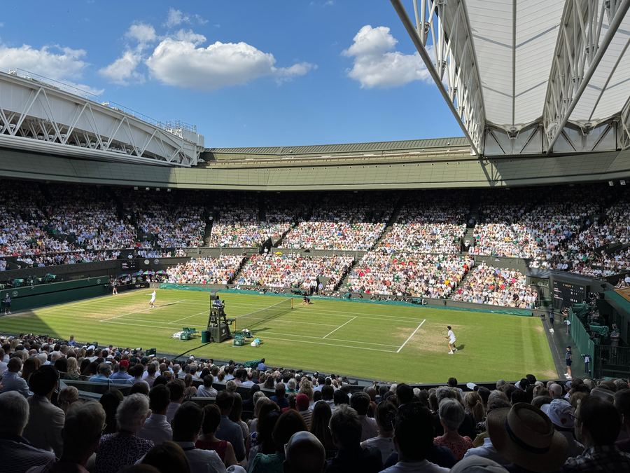 Centre Court at Wimbledon under blue skies with a full crowd